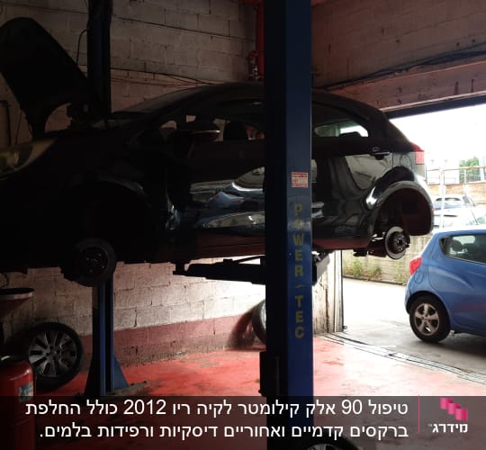 רכב מורם על ליפט במוסך עם מכסה מנוע פתוח